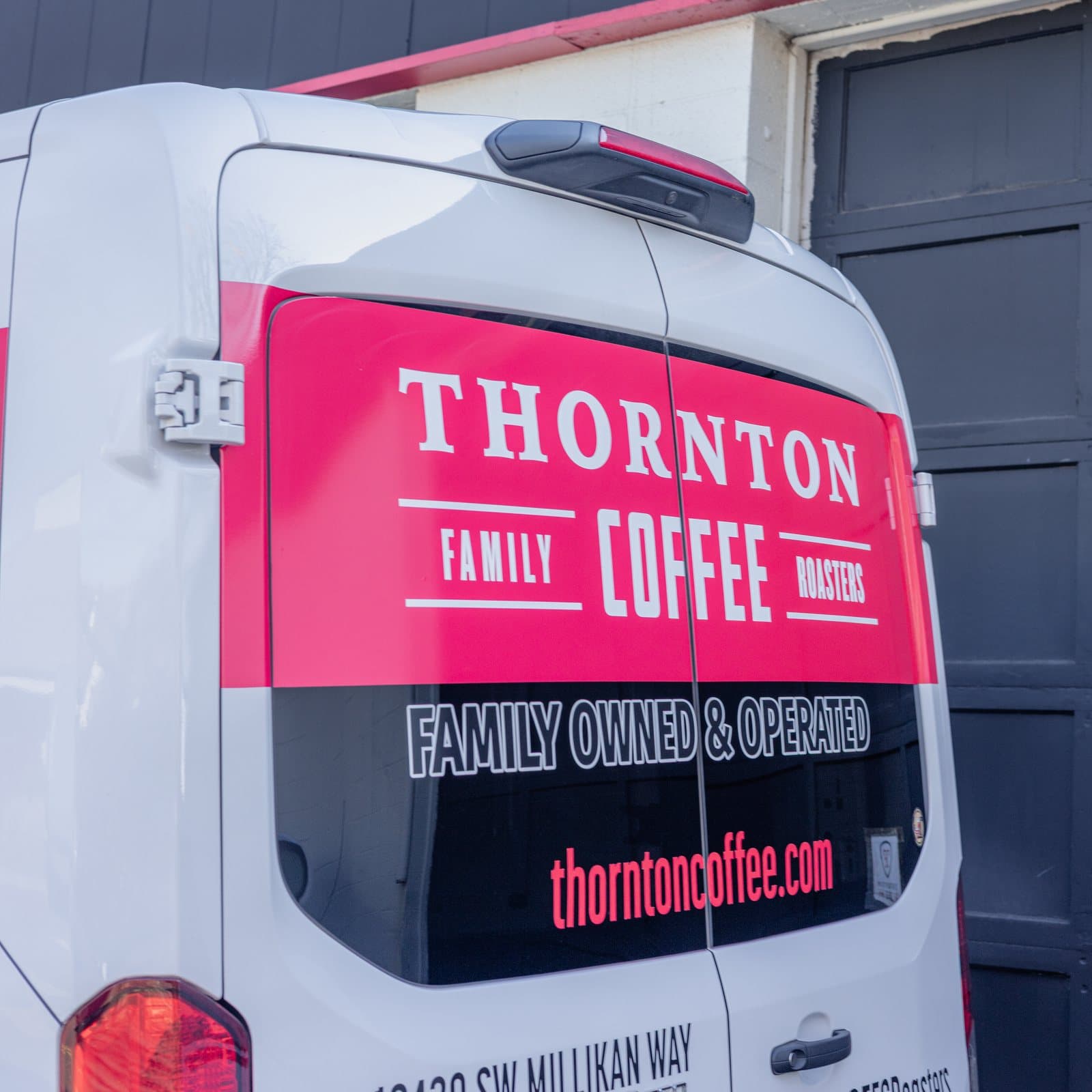 The rear doors of a white van with a printed panel across the window and lettering below it