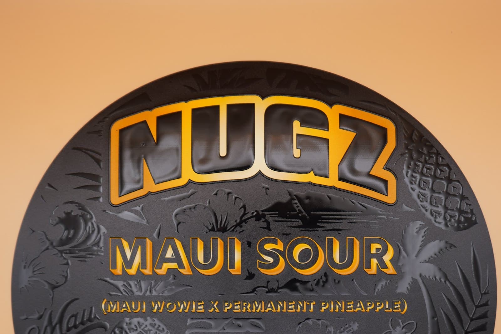 A round black label seen close up, with raised glossy tropical artwork and gold lettering