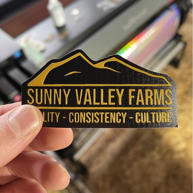 A die-cut label held up in front of the printers