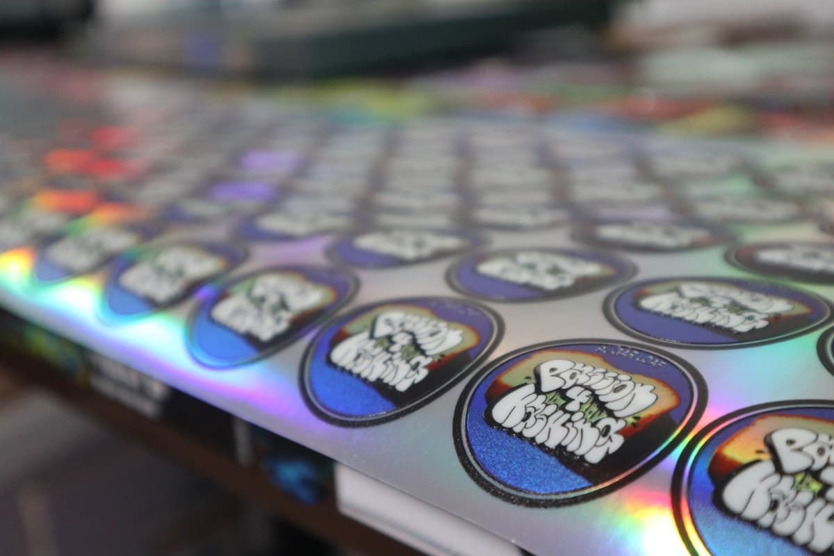 A sheet of round labels with a rainbow sheen, seen at a low angle