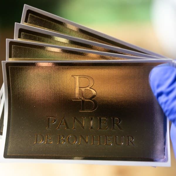A fan of dark printed pieces with gold lettering, held in a gloved hand